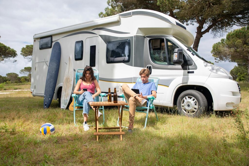 A couple enjoys a sunny day relaxing by their camper van in a picturesque outdoor setting in Portugal.